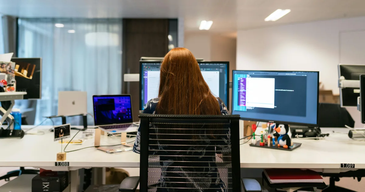 Chica programando en su puesto de trabajo, vista de espaldas